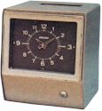Amano 6000-6100-6200 6500-6700 series in light sand color sheet metal case with brown clock dial. Card enters at top of machine. Note plastic frame piece around clock dial.